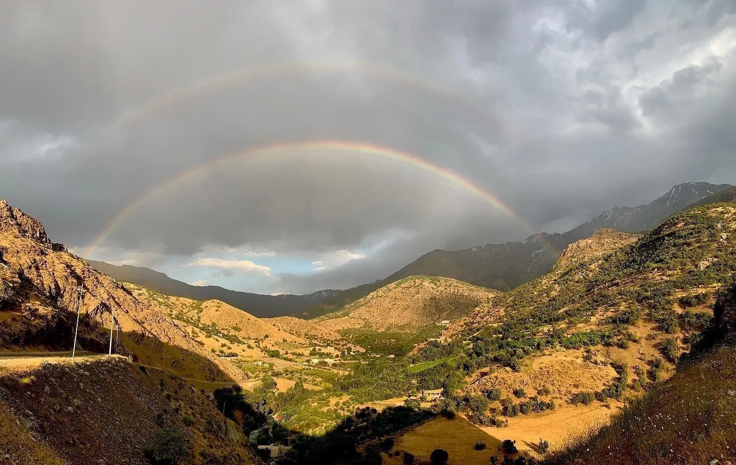 Berglandschap met een dubbele regenboog boven een dal